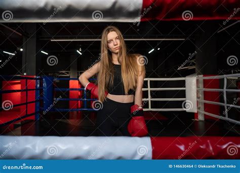 blonde caucasian fighter girl in red boxing gloves is posing on fight club boxing ring arkivfoto
