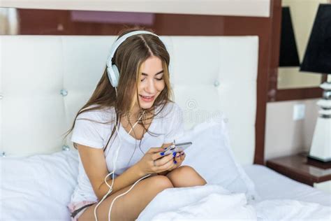 Young Beautiful Woman Relaxing In Her Bed Listening To Music Stock