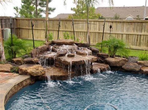 Often built with rocks or boulders (real and faux) as part of naturalistic pool design, waterfalls are one of the most popular water features when paired with swimming pools. pool waterfall ideas in the corner