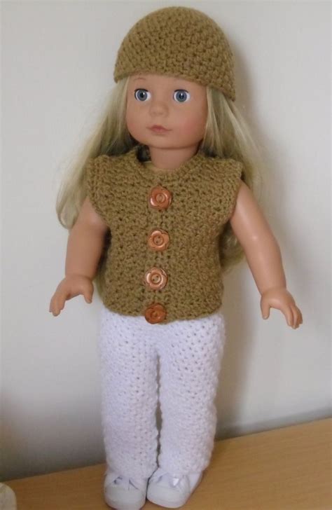 a doll with blonde hair wearing white pants and a brown knitted hat is standing on a wooden table