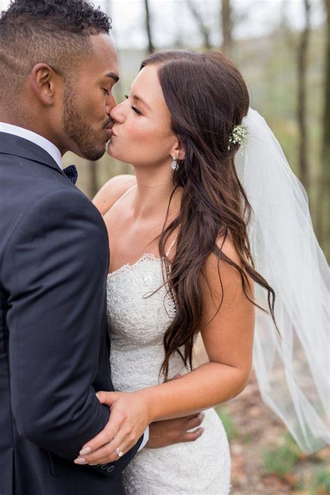 A Bride And Groom Kissing Each Other In Front Of The Trees At Their