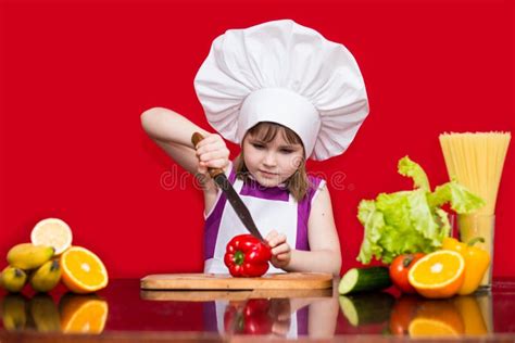 Happy Little Girl In Chef Uniform Cuts Vegetables In Kitchen Kid Chef
