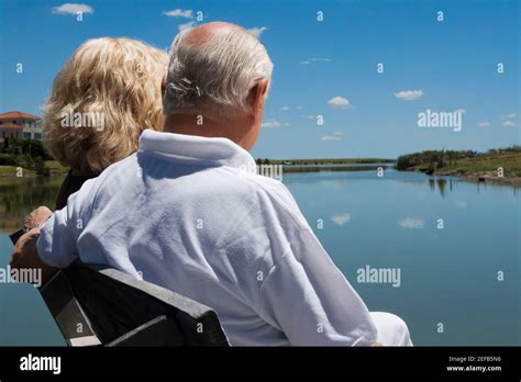 Senior Couple Sitting On A Bench At The Lakeside Stock Photo Alamy