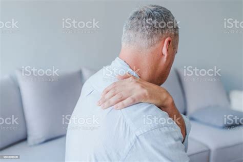 Man Suffering From Neck Or Shoulder Pain At Home Stock Photo Download