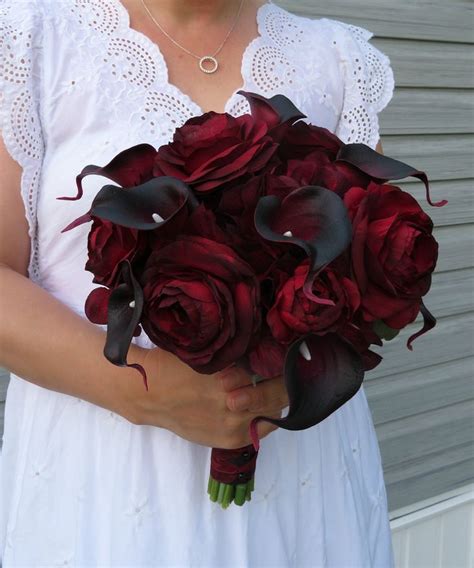 A Woman Holding A Bouquet Of Red Roses And Calla Lilies In Her Hands
