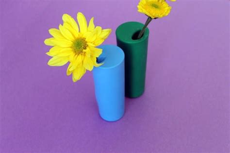 Two Blue Vases With Yellow Flowers In Them On A Purple Tableclothed Surface