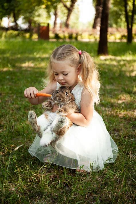 Little Cute Baby Girl Feeds Carrots Fluffy Pet Rabbit Care And Living