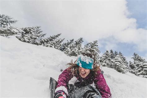 Woman Sliding Down A Snow Covered Slope In A Canadian Forest Stock Photo