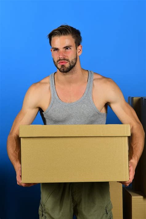 man standing among cardboard boxes and holding one guy with beard and concerned face holding