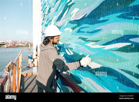 graffiti künstler malt eine weiße wand in großer höhe in wellen graffiti nach allen regeln
