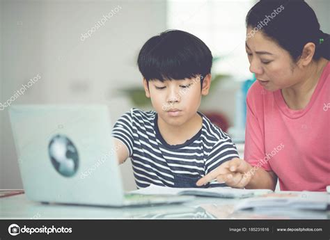 Asian Boy With Mother Teaching And Learning Your Homework At Home Stock
