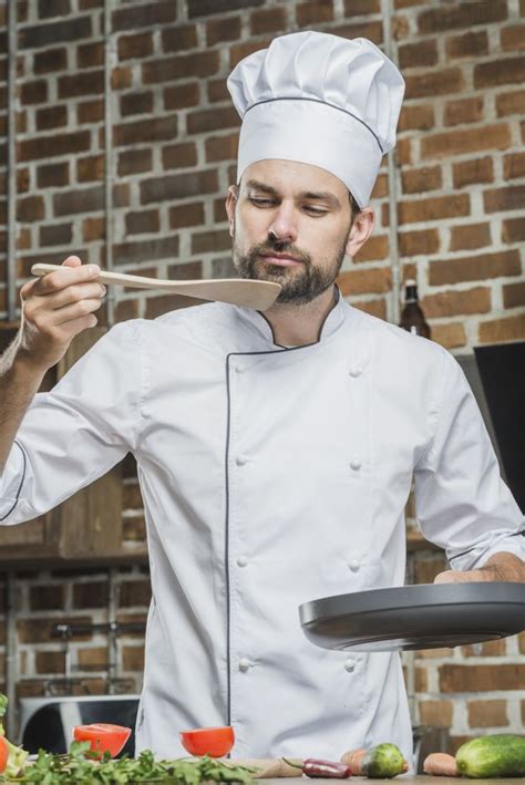 Free Photo Portrait Of Male Chef Standing In Kitchen Tasting Food