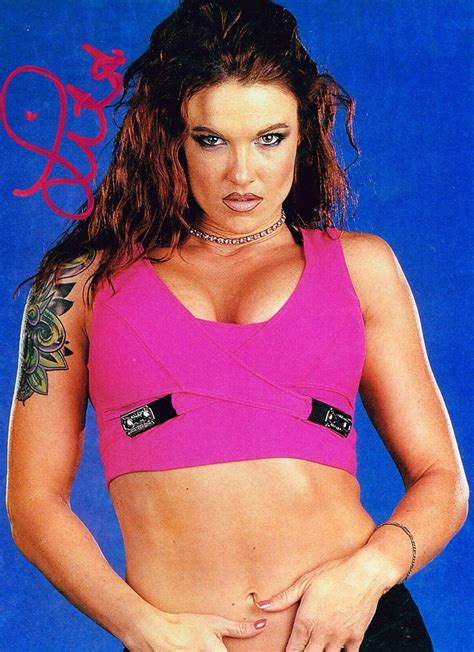 A Woman In A Pink Top With Tattoos On Her Arm And Chest Is Posing For The Camera