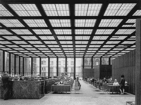 Black And White Photograph Of People Sitting At Tables In A Large Room