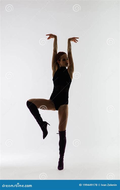Young Beautiful Flexible Female In Black Jumpsuit And High Heels Is