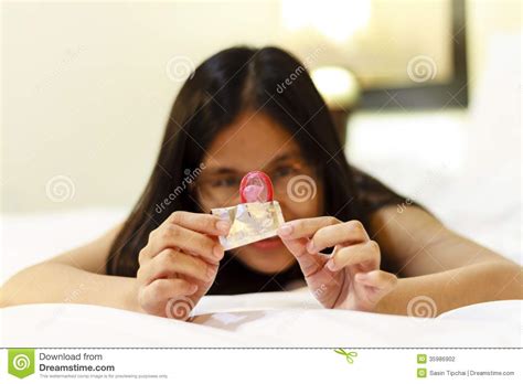 Asia Woman Opening A Condom On Her Bed Stock Photography Image