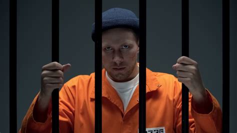Angry Caucasian Prisoner With Scared Face Looking Through Cell Bars