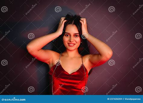 Close Up Photo Of A Beautiful Happy Brunette Girl In Red Clothes Touching Her Hair Looking At