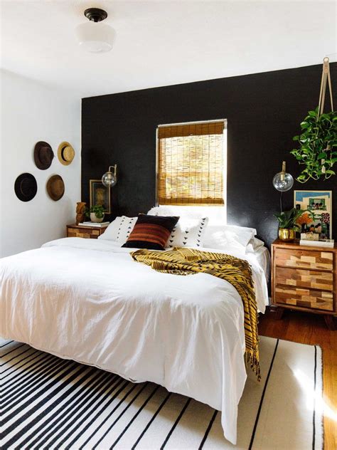 A Bedroom With Black Walls White Bedding And Striped Rugs On The Floor