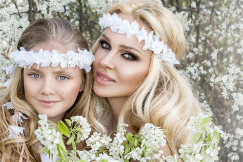 Beautiful Young Mother With Her Daughter Dressed In Spring Clothes And Wreaths Of Flowers Stock