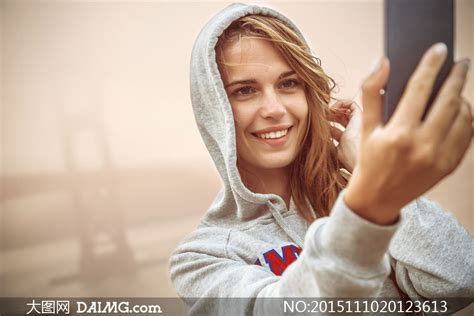 在对着手机自拍的帽衫女子高清图片 大图网图片素材