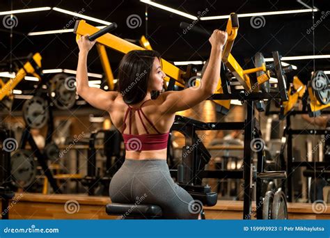 Fitness Brunette Girl Is Sitting And Doing Shoulder Exercises In