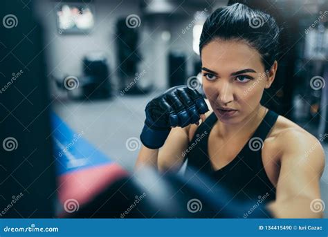 Top View Of Strong Brunette Attractive Female Trainer Punching A Bag With Kickboxing Gloves In