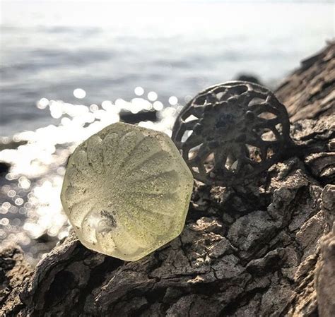 A Piece Of Glass Sitting On Top Of A Rock Next To The Ocean