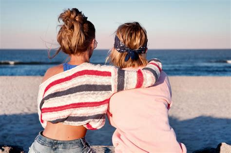 Two Young Girls Best Friends Sitting Together On The Beach At S Stock
