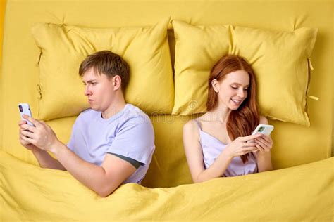 Couple Lying Back To Back In Bed And Using Smartphones At Night Have