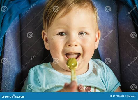 Beautiful Happy Baby Boy Eating Porridge Food With A Spoon Stock Photo