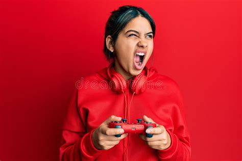 Young Latin Woman Playing Video Game Holding Controller Angry And Mad