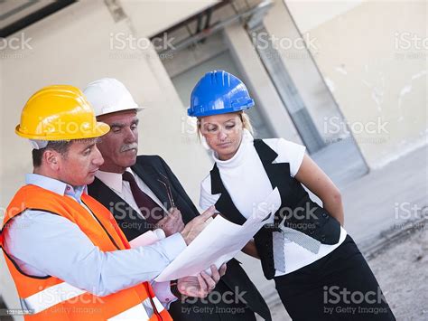 Group Of Businesspeople Reviewing Blueprints Together On Construction