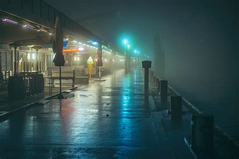 A Foggy Night On The Boardwalk With Benches And Tables In The