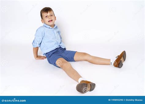 The Child Is A Boy Sitting On The Floor With His Legs Outstretched