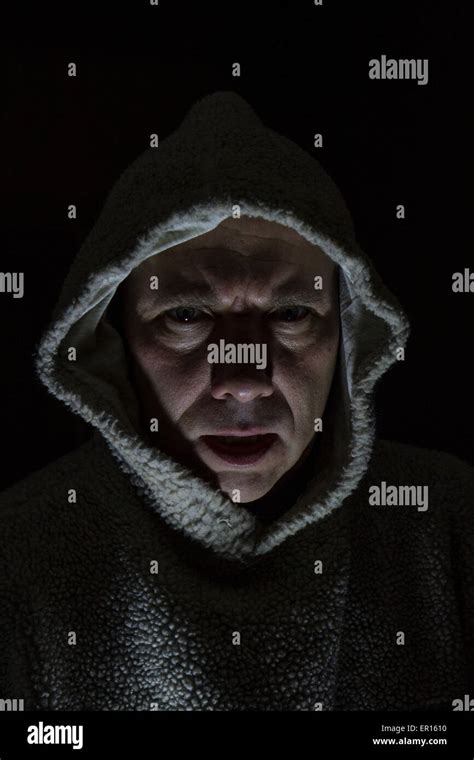 Scary Man With Hood Looking Mean With Dark Background And Face Lit