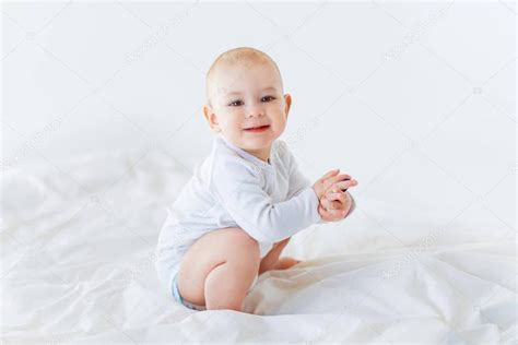 Little baby boy sitting on window in white towel and diaper in winter. Baby boy sitting on bed — Stock Photo © LenaMiloslavskaya ...