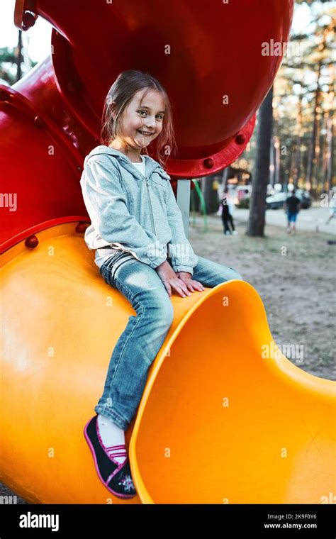 Little Girl Playing On A Slide In The Playground Hi Res Stock