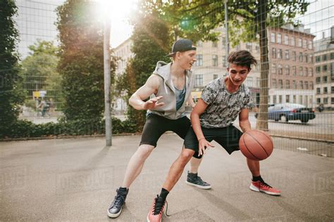 Teenagers Playing Basketball On Outdoor Court And Having Fun Young Man