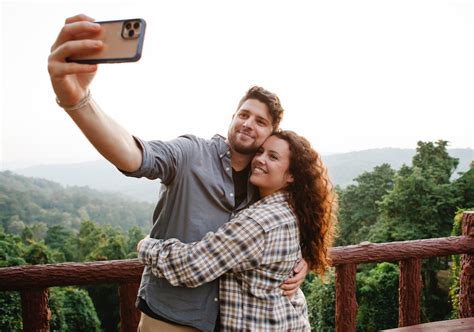 Cheerful Young Couple Hugging While Taking Selfie On Terrace In Forest