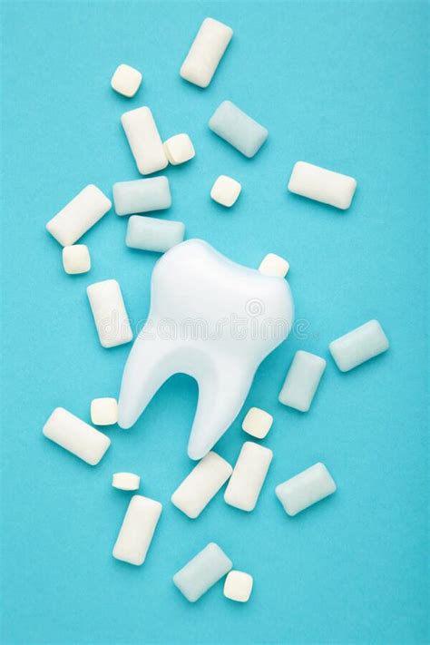 White Healthy Tooth Model And Heap Of Chewing Gums On Blue Background