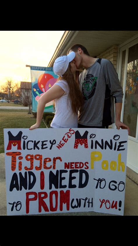 A Man And Woman Kissing In Front Of A Sign That Reads Mickey Mouse