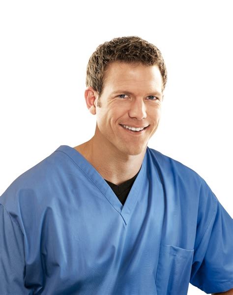A Man In Blue Scrubs Is Smiling At The Camera With His Hands On His Hips