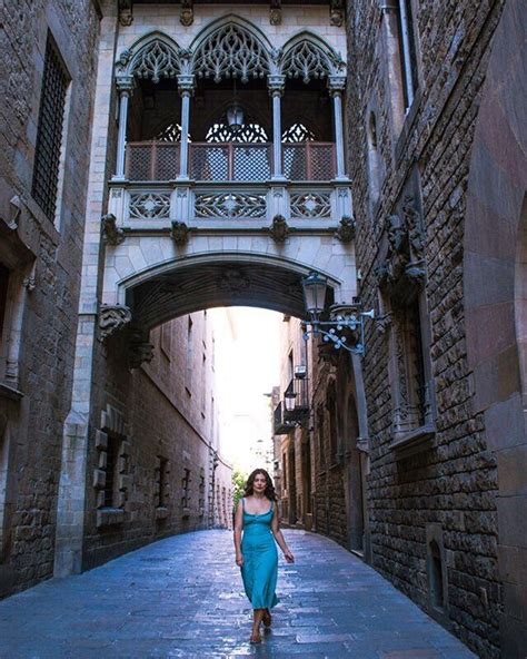 A Woman In A Blue Dress Walking Down An Alley Way With Arches And Railings