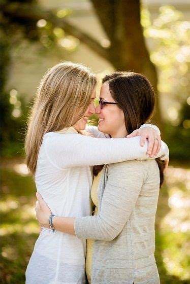 Two Women Hugging Each Other In Front Of A Tree