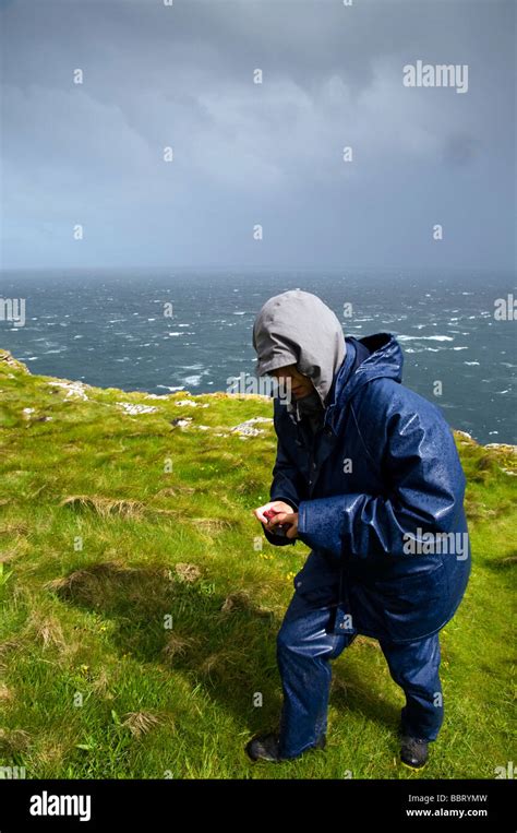 Girl Wearing Storm Jacket And Trousers Walking Through The Green Fields With The Ocean In The