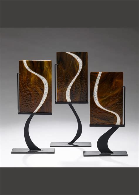 Three Metal Sculptures With Brown And White Swirls On Them One Is Standing In Front Of The Other