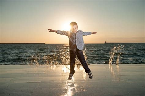 Healthy Little Kid Jumping On Sea With Waves Background In Springtime