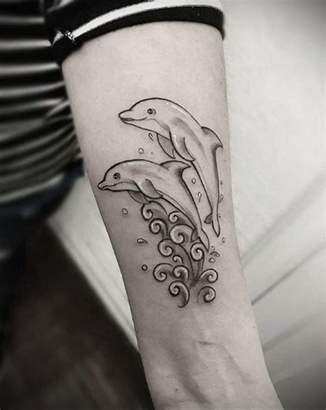 two dolphins jumping out of the water tattoo on the left forearm and right arm with waves coming