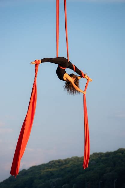 premium photo beautiful and flexible female circus artist dancing with aerial silk on a sky